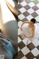 A woman in a white tutu sitting on a checkered floor.