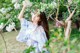 A woman in a blue kimono standing in front of a tree.