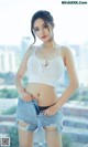 A woman in a white top and denim shorts posing for a picture.