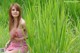 A woman in a red and white striped dress sitting in tall grass.