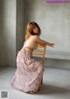 A woman sitting on a wooden chair in a long dress.