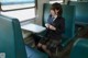 A woman in a school uniform sitting on a train.