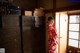 A woman in a red kimono standing in front of a door.