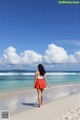 A woman walking on a beach near the ocean.