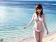 A woman in a white bikini standing on a beach.