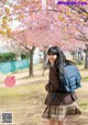 A young woman with a backpack standing in front of a tree.