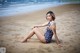 A woman in a bathing suit sitting on the beach.