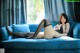 A woman laying on a blue couch with her legs crossed.