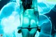 A woman in a black bikini standing in front of a blue background.