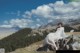 A woman in a white dress sitting on a rock in the mountains.