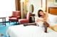 A woman sitting on a bed in a hotel room.