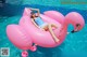 A woman laying on a pink flamingo float in a pool.